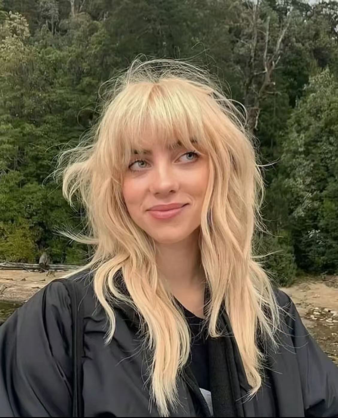 Billie Eilish messy blonde bangs and wavy layers hairstyle