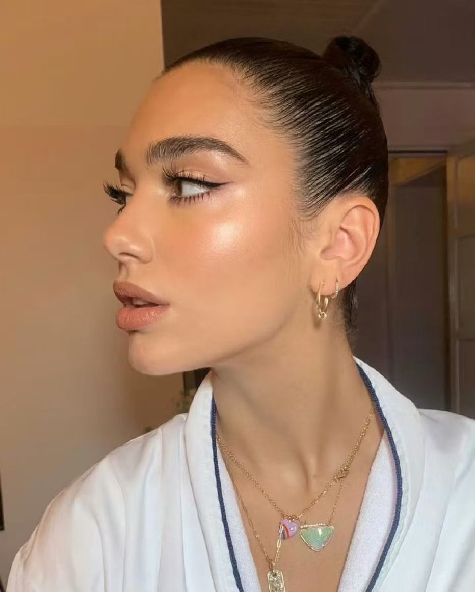 Dua Lipa sleek bun hairstyle with glossy side profile